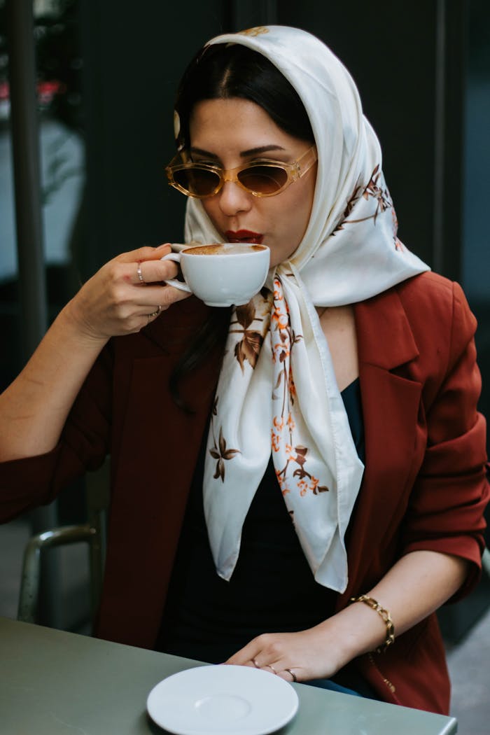 A stylish woman in a headscarf enjoys coffee in an Istanbul cafe, exuding a modern vibe.