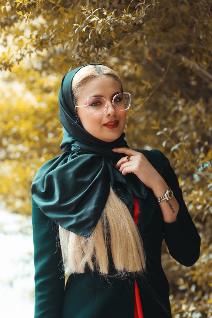Portrait of a fashionable woman wearing a headscarf and glasses in an outdoor setting.